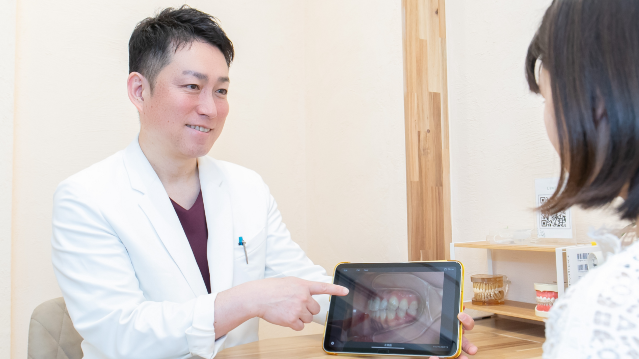 モニター画面を見せながら治療計画を説明する歯科医師